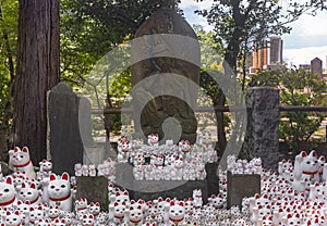 Statue of Nyoirin Kannon Bosatsu and manekineko cats in Buddhist gotokuji temple.