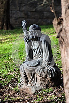 Statue of an old man, sitting on a rock in the garden of the Nan Tien Temple, Wollongong, Australia