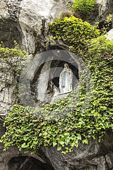 Statue of Our Lady of Immaculate Conception with a rosary in the Grotto of Massabielle in Lourdes
