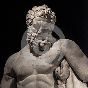 Statue of powerful Hercules, closeup, isolated at black background