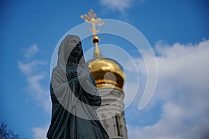 statue of a praying nun against the background of an Orthodox church