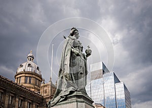 Statue of queen Victoria in Victoria Square, Birmingham England UK. Town hall behind and bronze statue on stone plinth