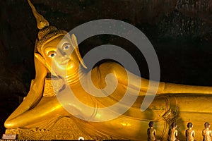 Statue of Reclining golden Buddha in cave