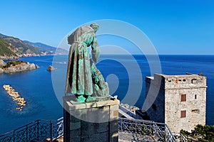 The statue of Saint Francis of Assisi caressing the wolf of Gubbio and Torre Aurora in Monterosso Al Mare, Cinque Terre, Italy.