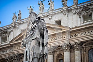 Statue of Saint Peter and Saint Peter`s Basilica at background in St. Peter`s Square, Vatican City, Rome, Italy