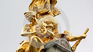 Statue of sitting gold female holding wheel