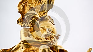 Statue of sitting gold female holding wheel