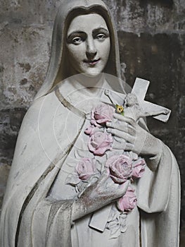 Statue of the Virgin Mary carrying roses and a crucifix.