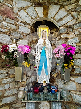 Statue of virgin mary colourfull flowers holy Madonna photo