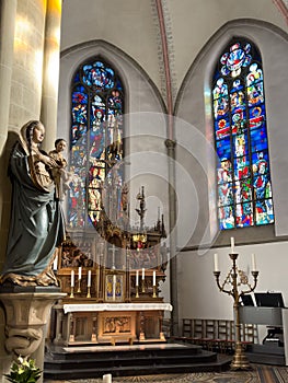 Statue Virgin Mary and Jesus, altar and stained glass windows of the Church of St. Peter and Paul in Ratingen, Germany.