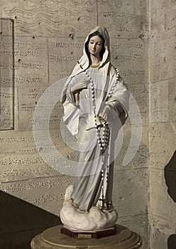 Statue Virgin Mary with a rosary draped over her shoulders in the Holy Savior Church in Castellina in Chianti, Italy.