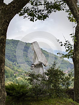 A statue of the Virgin Mary in the small Lunigiana town of Fivizzano, outdoors, framed by trees. Rural faith.