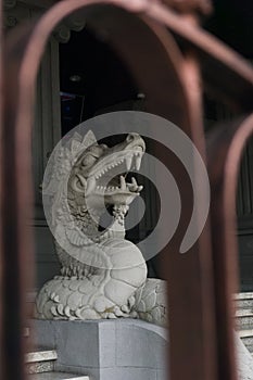A statue of a white dragon head made of stone carved into a dragon. located in front of a building