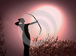 Statue of a woman Archer Silhouette with a bow target the sun. photo