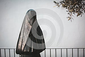 Statue of a Woman Dressed in Black Cloak and Head Veil `La Cobijada` from her back photo