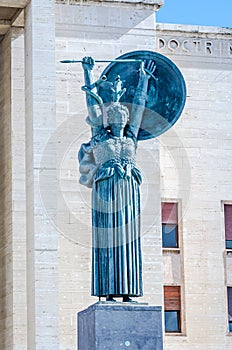 Statue of a woman with a sword and shield behind which climbs a snake made of marble which is installed in the University of Rome