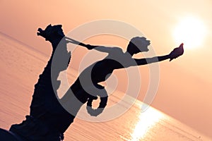 Statue of a Young Girl Holding a Shell and Riding a Seahorse Hippocampus in front of Lake Leman Vevey at Sunset