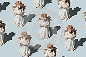 statues of angels praying on a blue background. Christmas pattern