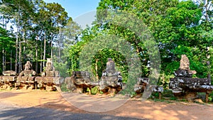 Statues on bridge to Angkor Thom, Cambodia. Demons fallen apart on Temple of Angkor Thom, Cambodia.