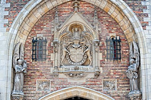 Statues and coat of arms over archway.