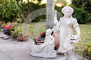 Statues in a garden next to flower pots in a summer day with sunset light photo