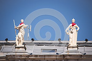 Statues on the roof of the city hall of Bayonne with a red scarf during the Summer festival