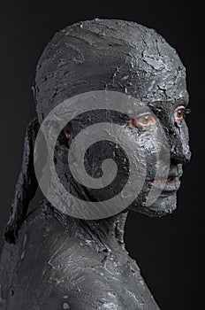 Statuesque woman in wet clay. Spa treatment.
