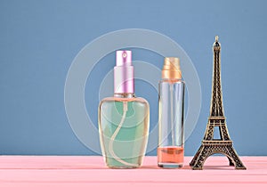 A statuette of the Eiffel Tower, bottles of perfume on a blue pastel background, minimalist trend, space for text, beauty