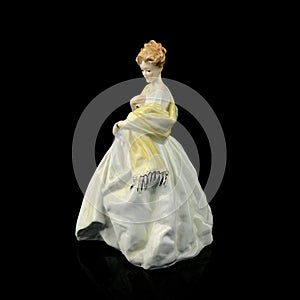 Statuette of a girl in a yellow dress on a black background.