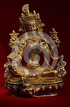 Statuette of Green Tara on a red background. photo
