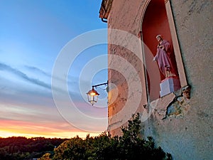 Statuette of Jesus in the wall with a vintage lantern at sunset