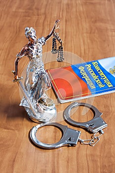 A statuette of Themis, the constitution of the Russian Federation and the handcuffs
