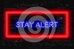 Stay Alert Neon sign on a dark brick background photo