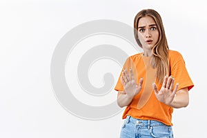 Stay away from me, keep distance. Portrait of alarmed, scared and reluctant young blonde woman, show stop, taboo gesture