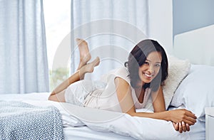 Stay in bed and stay happy. a young woman waking up in the morning and using her phone in bed.