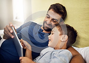 Stay connected to the people who matter. a young man using a digital tablet with his son at home.