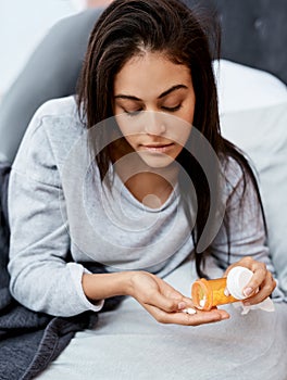 Stay the course until you make it through quarantine. a young woman taking medication while recovering from an illness