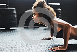 Stay determined and do whats best for you. a young woman doing pushups in a gym.