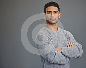 Stay determined. a handsome young man standing against a grey background.