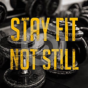 Stay fit not still message - with dumbbells on the rubberized floor as background. Gym motivation and hype words. Industrial