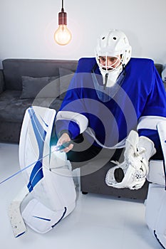 Stay at home. Cancellation of the World Cup and Olympics. Hockey goalie sitting in sofa