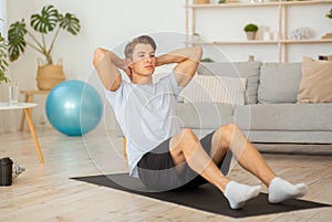 Stay at home and exercises for abs. Muscular guy doing workout on mat photo