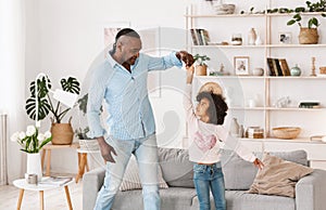 Stay home family fun. Cheerful older man with his granddaughter dancing in living room