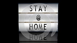 Stay @ home letters on a light box on reflective surface