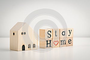 Stay home message on wooden dices and home wooden model. Stay home concept of self-isolation during the Covid-19 coronavirus outbr