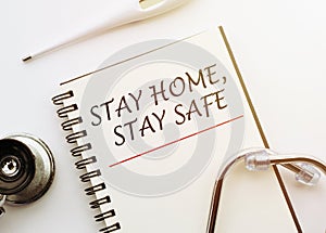 STAY HOME and STAY SAFE. COVID-19. Stay home save concept. Text written on a medical notebook. Background on the white table with