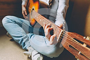 Stay Home Stay Safe. Young woman sitting at home and playing guitar, hands close up. Teen girl learning to play song and writing