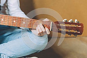 Stay Home Stay Safe. Young woman sitting at home and playing guitar, hands close up. Teen girl learning to play song and writing