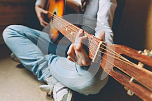 Stay Home Stay Safe. Young woman sitting at home and playing guitar, hands close up. Teen girl learning to play song and writing