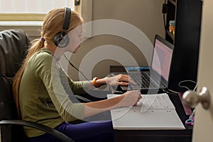 Stay home: Teenage girl sitting with laptop, notebook and tablet - online learning from home